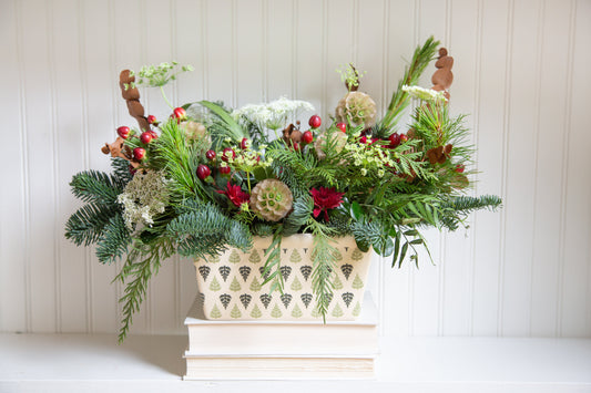 A winter flower arrangement including pine branches and red berries