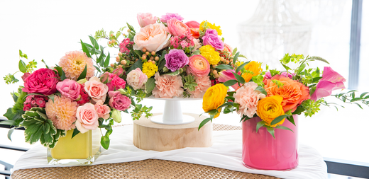 Brightly colored flowers in pink and yellow glass vases