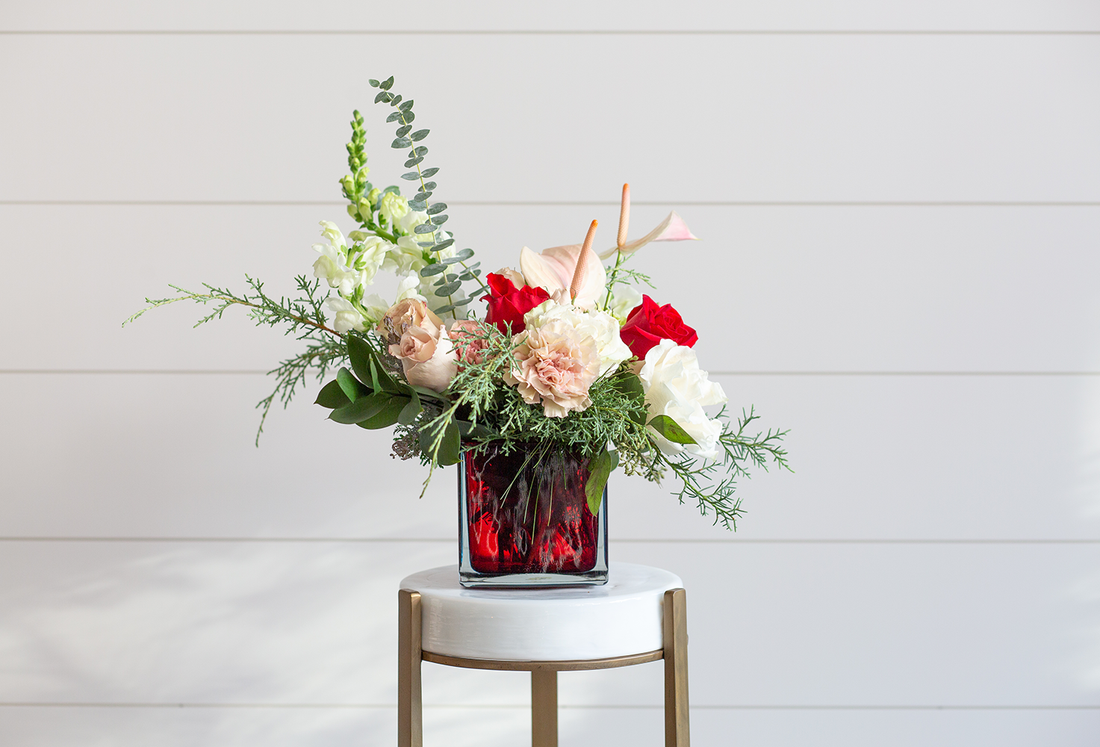  A red, pink, and white floral arrangement in a red vase